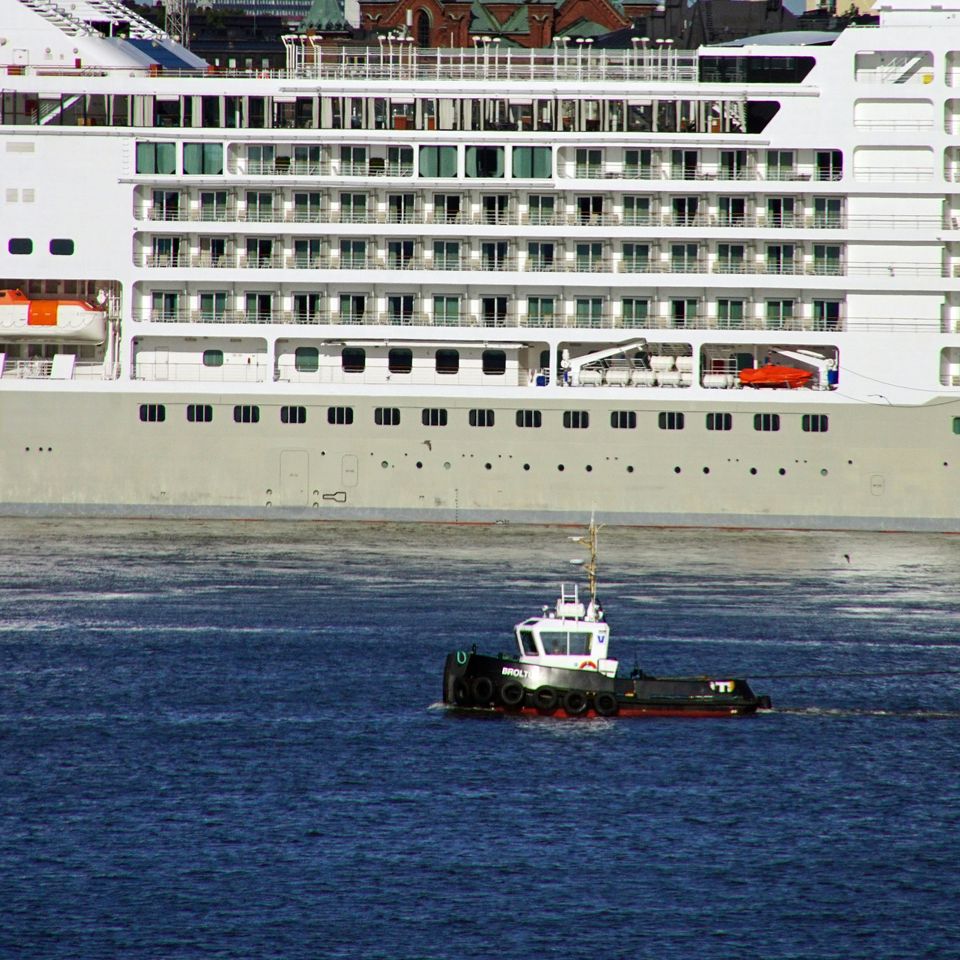 Harbour tug in front of a passenger ship